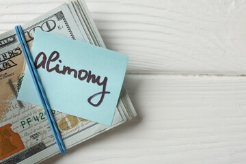 Note with word Alimony and money on white wooden table, top view. Space for text
