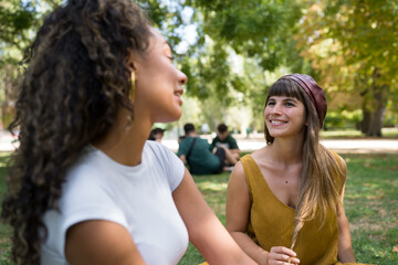 Fototapeta premium Smiling women friends talking together in park
