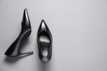 Fototapeta premium Pair of elegant black heels on light grey background, top view with space for text. Stylish shoes