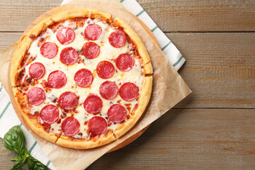 Delicious pepperoni pizza with fresh basil on wooden table, top view. Space for text