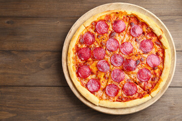 Delicious cut pepperoni pizza on wooden table, top view. Space for text