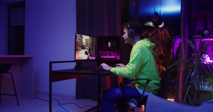 Young man in headphones playing video games on the computer