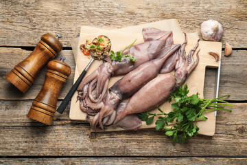 Raw squids, stuffing and parsley on wooden table, flat lay