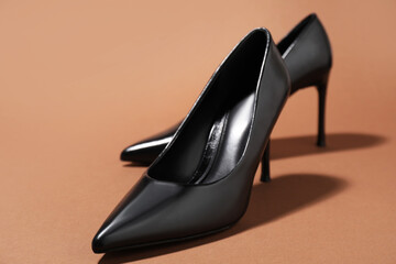 Pair of stylish high heeled shoes on brown background, closeup