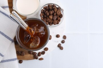 Tasty iced coffee, milk and beans on white table, flat lay. Space for text