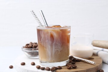 Tasty iced coffee with milk and beans on white table