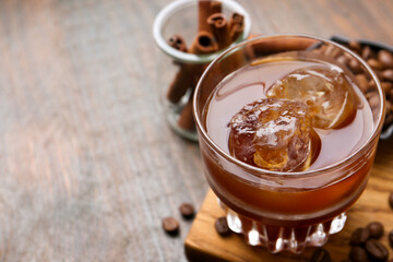 Tasty iced coffee and beans on wooden table, closeup. Space for text