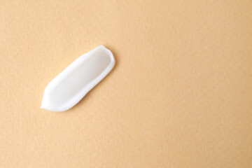 Sample of moisturizing cream on beige background, top view. Space for text