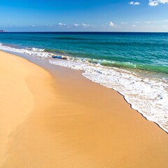 Obraz premium Sandy beach with foamy waves gently crashing on the shore under a clear sky