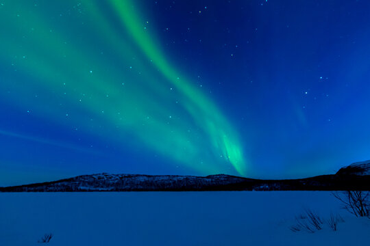 Leuchtende Nordlichter. Gr&uuml;n-violette Aurora Borealis tanzt &uuml;ber Landschaft und Himmel.