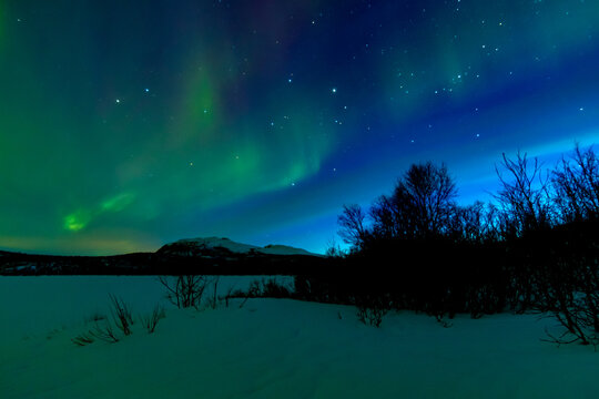 Leuchtende Nordlichter. Gr&uuml;n-violette Aurora Borealis tanzt &uuml;ber Landschaft und Himmel.