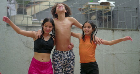 Smiling children of different ethnicities playing under water spray, enjoying laughter and holding...