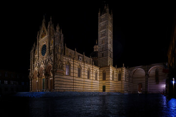 Naklejka premium Siena Cathedral illuminated at night, striped marble facade, vast empty square