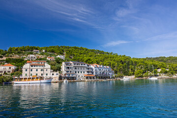 Coastal Mediterranean Village By Clear Blue Water With Boats And Green Hills, Stomorska, Croatia