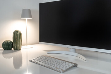 Modern and minimalist home office setup with a large blank monitor for mockup placement