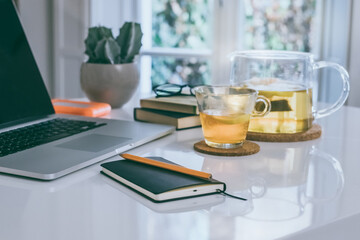 Morning time at home healthy breakfast laptop and cup of lemon tea on table. Natural meal at work in remote office, health hot drinks with computer freelance desktop workspace. Home working concept.