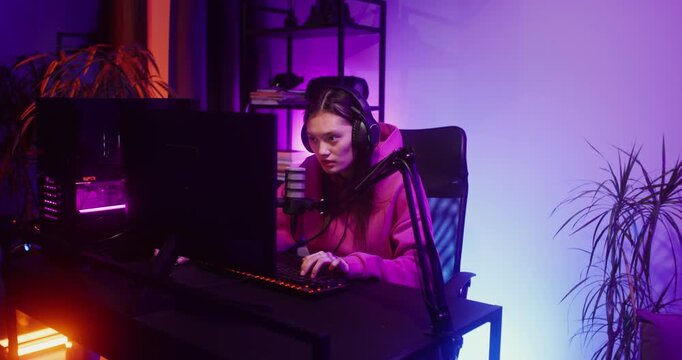 Young woman in headphones speaks into a microphone while looking at a computer screen