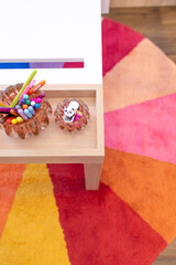Top view of vIbrant collection of pens and pencils in glass holders, displayed on a wooden tray. Perfectly blending functionality and design for a child's creative space.