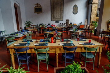 Colorful rustic dining hall with mismatched chairs, set tables, and historic decor