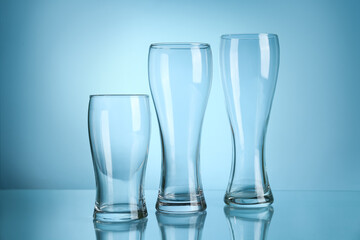 Clean glasses on table against color background