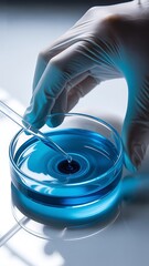 Hand in glove adds drop to blue liquid in petri dish pipette