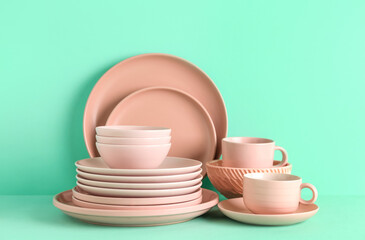 Clean cups with plates and bowls on color background