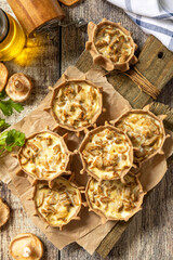 Rustic mushroom tartlets on wooden cutting board perfect for  appetizers. Top view flat lay background.