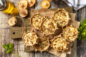 Rustic mushroom tartlets on wooden cutting board perfect for  appetizers. Top view flat lay background.