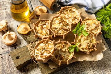 Rustic mushroom tartlets on wooden cutting board perfect for  appetizers.