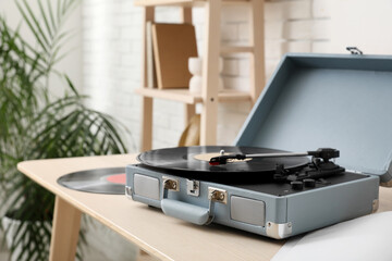 Record player with vinyl disks on wooden table
