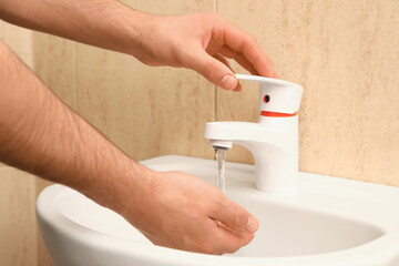 Man washing hands near sink in bathroom
