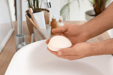Man with soap near sink in bathroom