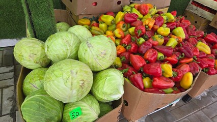 Fresh colorful bell peppers and cabbages displayed in outdoor market setting