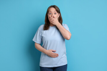 Fototapeta premium Woman suffering from stomach ache and nausea on light blue background