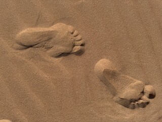 footprint in sand  Pair of human footprints deeply impressed in dry desert or beach sand texture