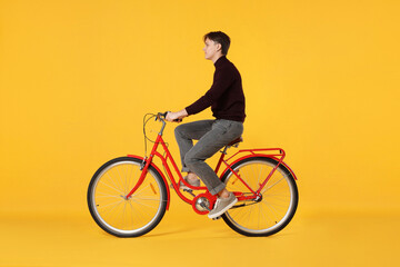 Handsome man riding red bicycle on orange background