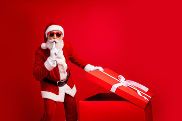 Surprised Santa Claus unveils a festive gift box on a vibrant red background, evoking holiday cheer