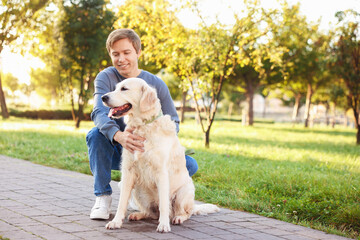 Man with his adorable golden retriever dog in park. Space for text