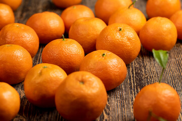 Unpeeled orange tangerines stacked together, a large number of ripe orange tangerines on the table