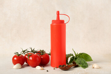 Bottle of tasty ketchup with garlic, fresh tomatoes, peppercorns and basil leaves on light background