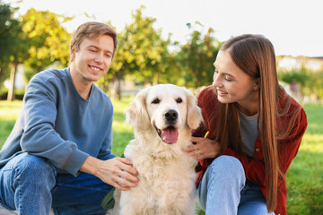 Happy couple with their adorable golden retriever dog in park