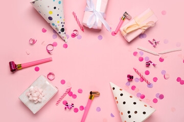 Frame made of cone party hats with gift boxes, whistles, candles and decor on pink background
