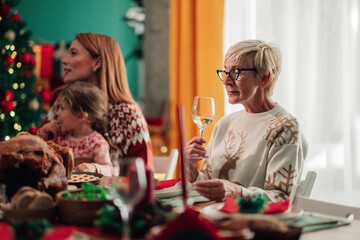Grandmother drinking wine at christmas dinner with family