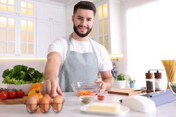 Smiling man cooking at table in kitchen