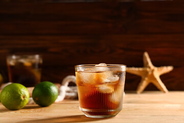 Glass of cold Cuba Libre cocktail on wooden background