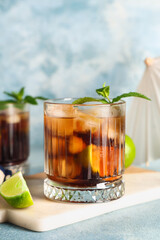 Glass of cold Cuba Libre cocktail on blue grunge background