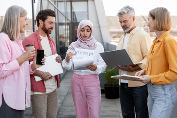 Diverse business team collaborating outdoors discussing reports