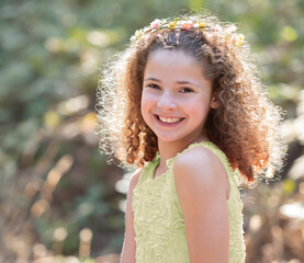 Outdoor summer portrait adorable, smiling little girl with naturally curly hair wearing green dress
