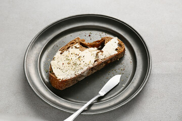 Slice of fresh bread with butter and herbs on grey grunge background