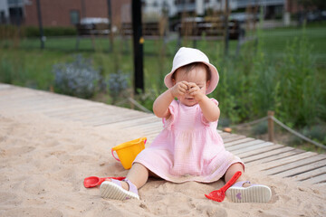 adorable child in pink dress enjoys playful exploration of sand with colorful toys in outdoor park setting on a bright sunny day, tranquil, moment, leisure, family, calm, natural, relaxing